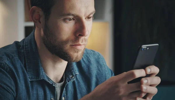 Hombre joven mirando la pantalla del teléfono celular —  Fotos de Stock