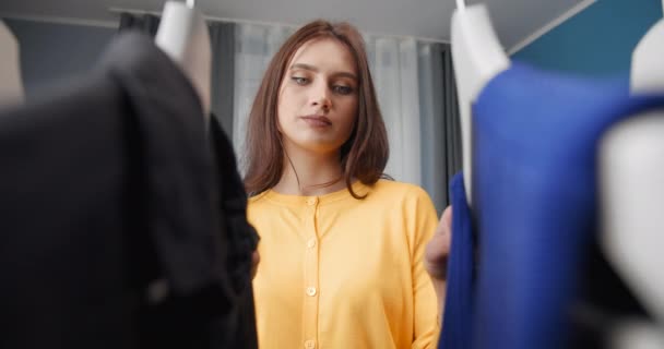 Young woman standing in closet and choosing clothing — Stock Video