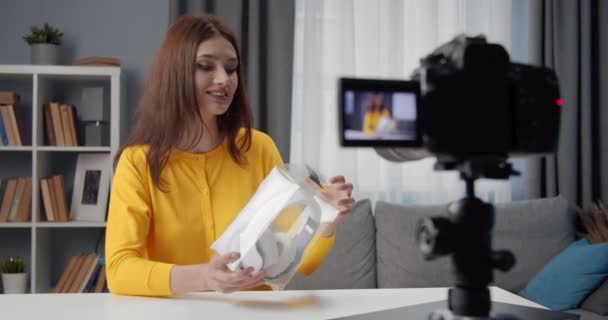 Mujer joven grabando vídeo mientras desempaqueta auriculares — Vídeos de Stock