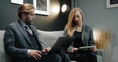 Kanepede modern aletlerle çalışan iş adamları.