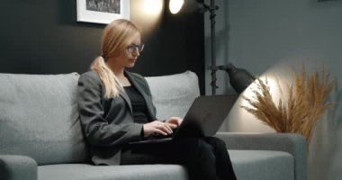 Koltukta oturan ve bilgisayarla çalışan kendine güvenen bir kadın.