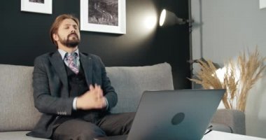 Yorgun adam dizüstü bilgisayarla uğraşırken boynundaki acıyı hissediyor.