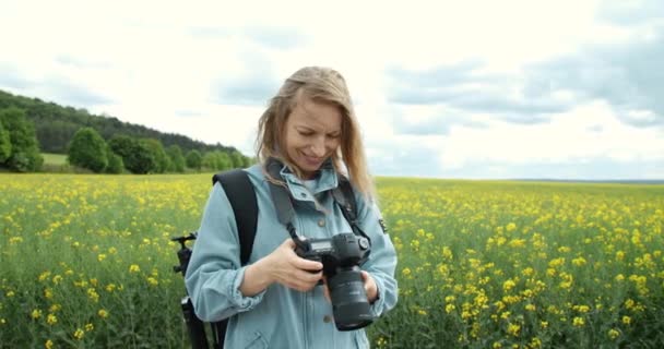 Mosolygó hölgy fotózza a természetet tavasszal — Stock videók