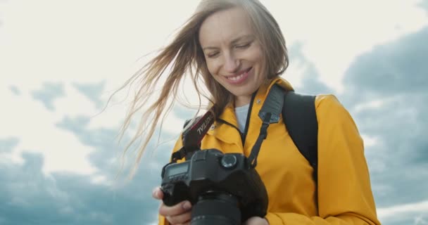 Vrolijke dame die foto 's op camera buiten bekijkt — Stockvideo