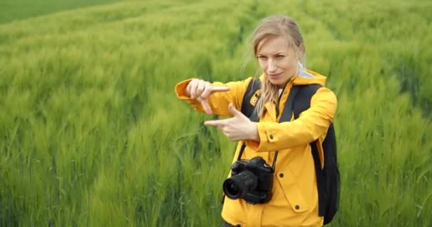 밀 밭 사이에서 손가락으로 틀을 만드는 사진 작가 — 비디오