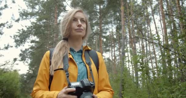 Attraktiv dam står bland gröna träd och tar bilder — Stockvideo