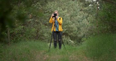 Olgun bir bayan yeşil ormanın manzarasını çekiyor.