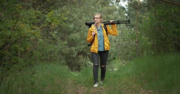 Donna che porta sullo zaino e treppiede per sparare alla foresta — Video Stock