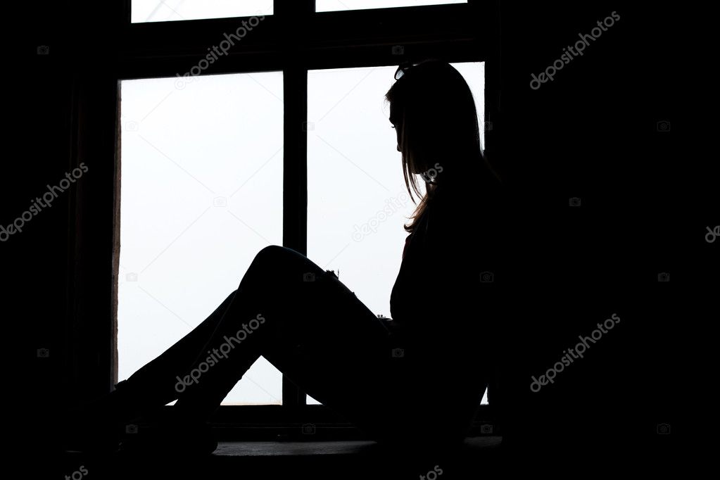Woman looking through window sitting on the window sill