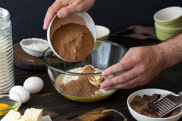 Человек готовит смешивает пищевые ингредиенты для приготовления шоколадного теста — стоковое фото