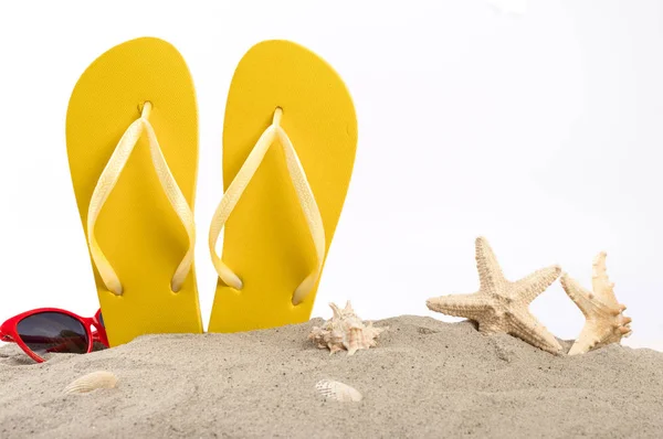 Strand slippers met zonnebril, schelpen en zeesterren in het zand — Stockfoto
