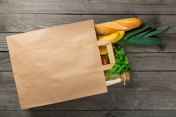 Їжа в паперовій сумці на дерев'яному фоні — стокове фото
