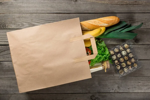 Comida diferente em saco de papel no fundo de madeira — Fotografia de Stock