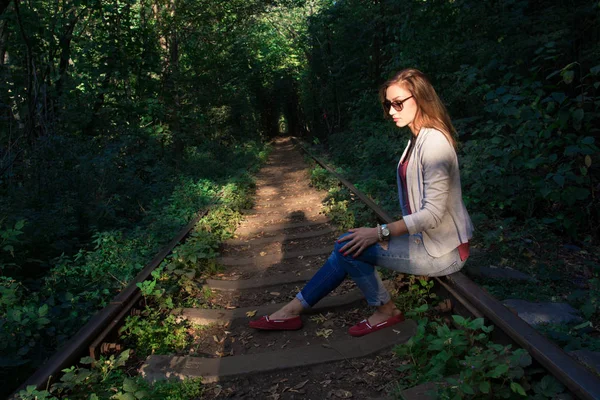 Грустная молодая женщина сидит на железнодорожных путях — стоковое фото