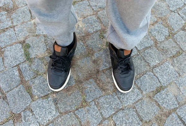 Male legs in black leather sneakers close up — Stock Photo, Image