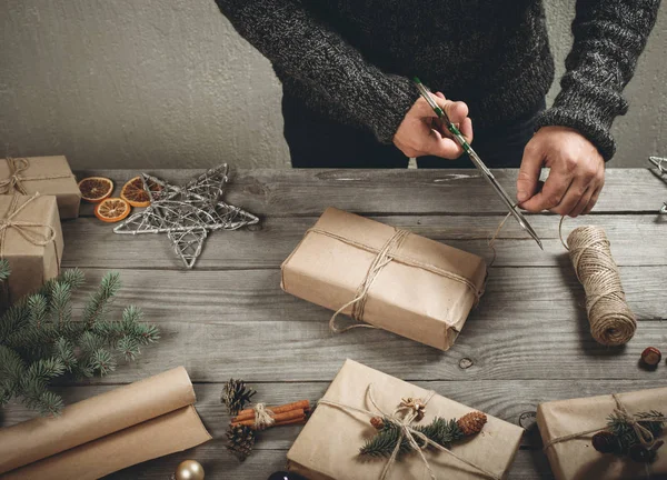 Manliga händer inslagning julklapp på träbord — Stockfoto