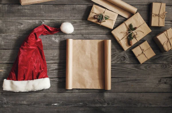 Blad papier met Kerstcadeaus en kerstmuts, bovenaanzicht — Stockfoto