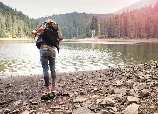 Молодая женщина стоит у горного озера, наслаждаясь моментом — стоковое фото