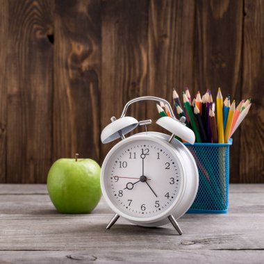 Retro çalar saat ile renkli kalemler ve yeşil elma