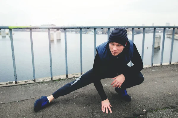 Hombre ejercitando ejercicio físico en el puente de la ciudad en un día fresco — Foto de Stock