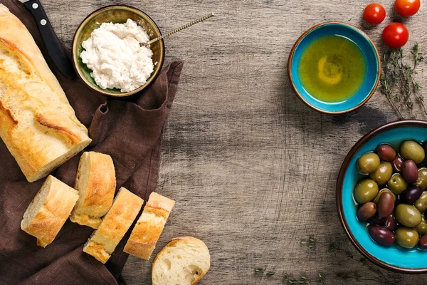 Cornice di baguette, olio, olive, aglio, erbe aromatiche, formaggio di capra, toma — Foto Stock