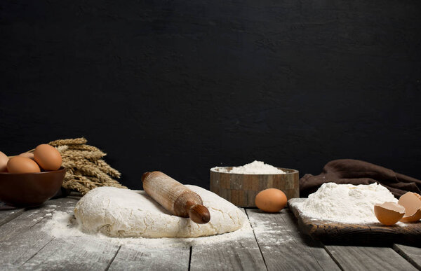 Dough with wooden rolling pin, flour and eggs