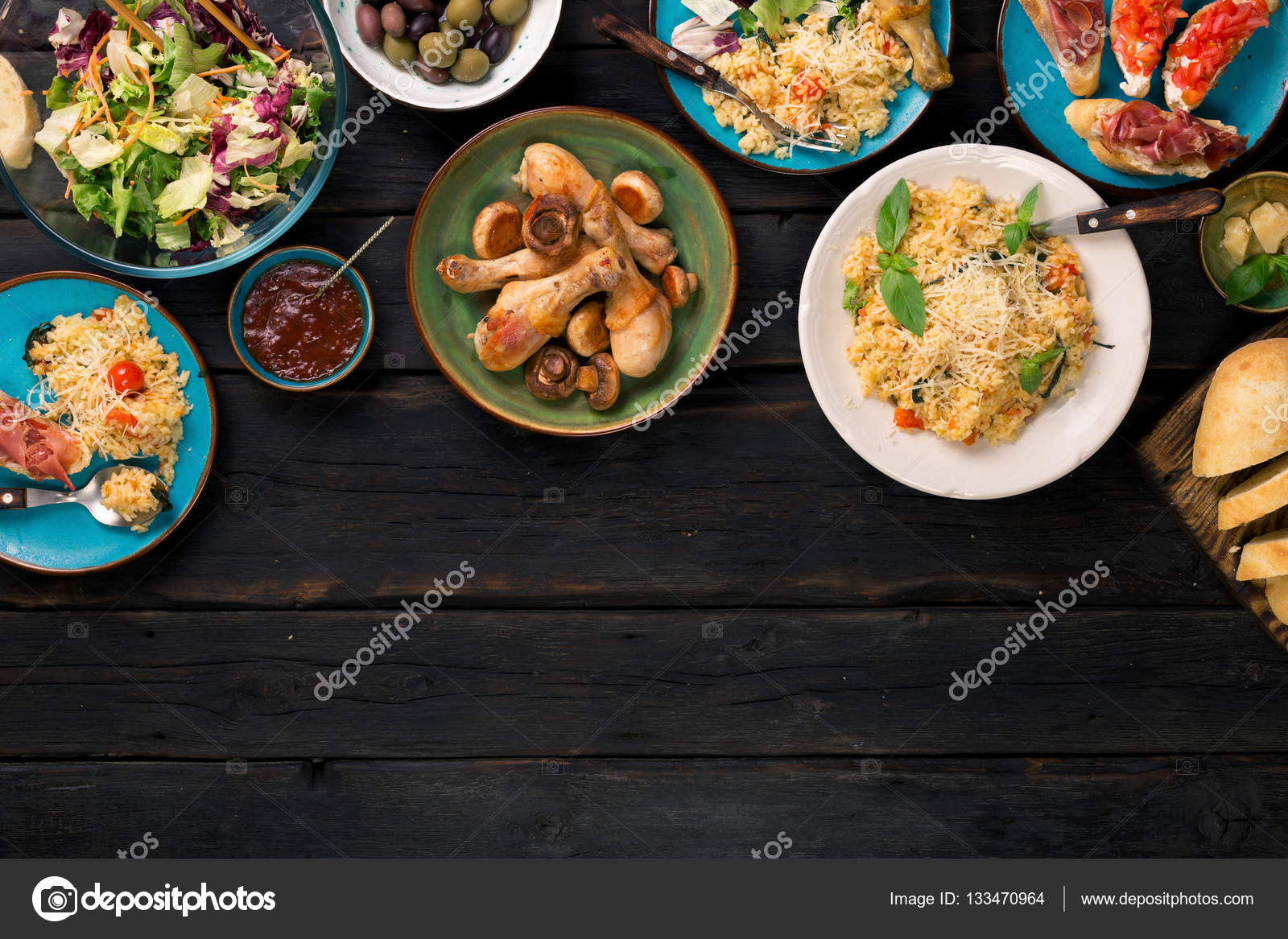 Risotto, roasted chicken legs and snacks on dark wooden table Stock Photo by ©KucherAndrey 133470964