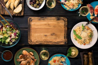 Doğrama tahtası, risotto, kavrulmuş tavuk budu, aperatifler ve beyaz 