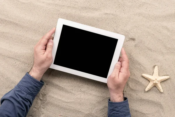 Man holding tablet with blank screen lying on the beach — Stock Photo, Image