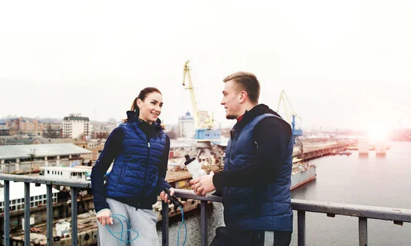 Una pareja de chalecos azules hablando en un puente de la ciudad — Foto de Stock