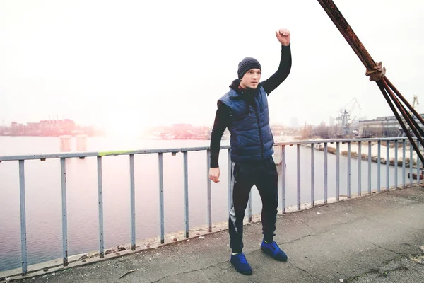 Atleta calentándose antes de entrenar en un puente de la ciudad — Foto de Stock