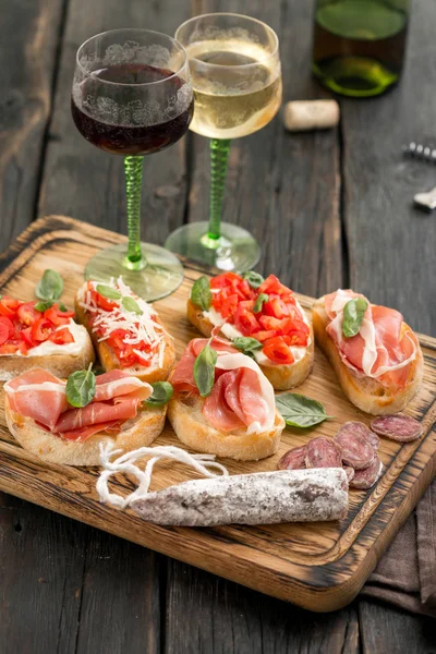 Set snacks italiens servis sur une planche en bois avec du vin — Photo