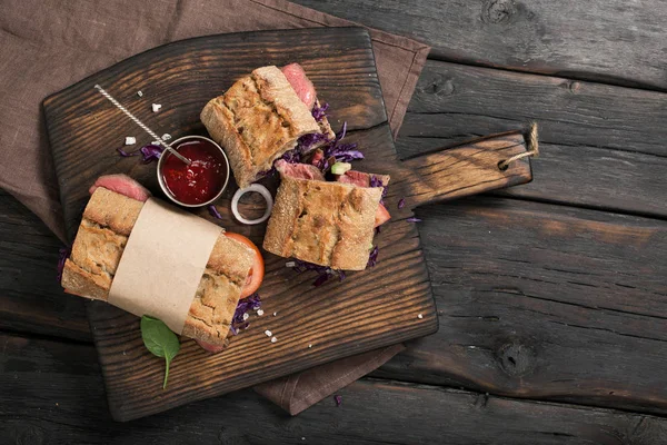 Сэндвичи с мясом гриль на коричневой старой кухонной доске — стоковое фото