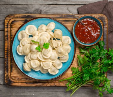 Mantı ve ahşap bir tahta üzerinde kırmızı sos ile çanak