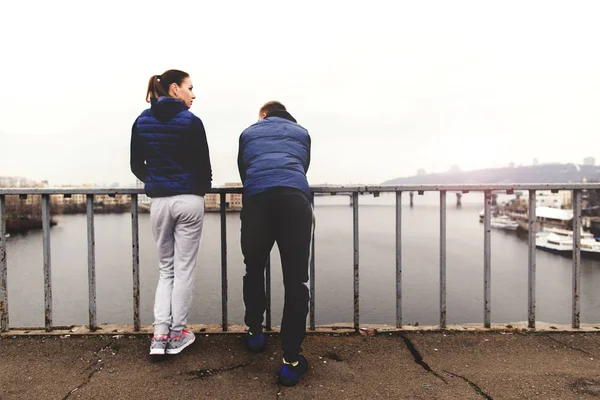 Pareja en ropa deportiva está de pie en el puente — Foto de Stock
