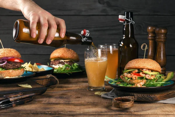 Cerveza de cerveza en la mesa de madera con una variedad de hamburguesas — Foto de Stock
