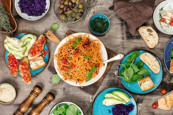 Ahşap masa üzerinde farklı İtalyan yemekleri ile makarna