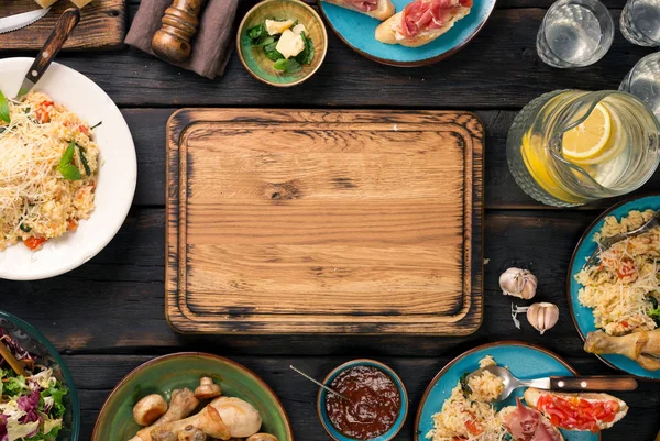 Порожня обробна дошка на темному дерев'яному столі з різноманітною їжею — стокове фото