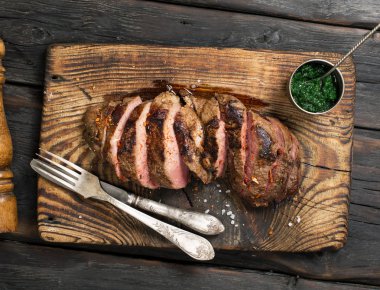 Sığır eti biftek chimichurri soslu ahşap arka plan üzerinde dilim