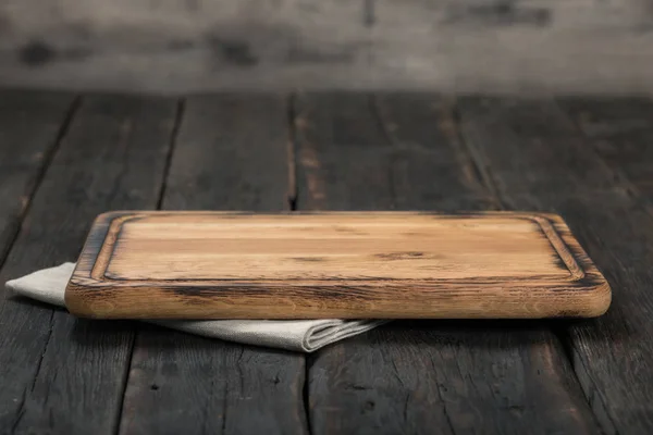 Tabla de cortar vacía con servilleta de tela en mesa de madera — Foto de Stock