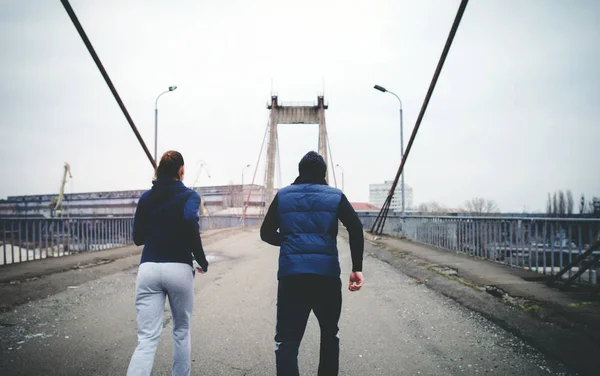 Pareja de jóvenes deportes corriendo en el puente, vista trasera — Foto de Stock