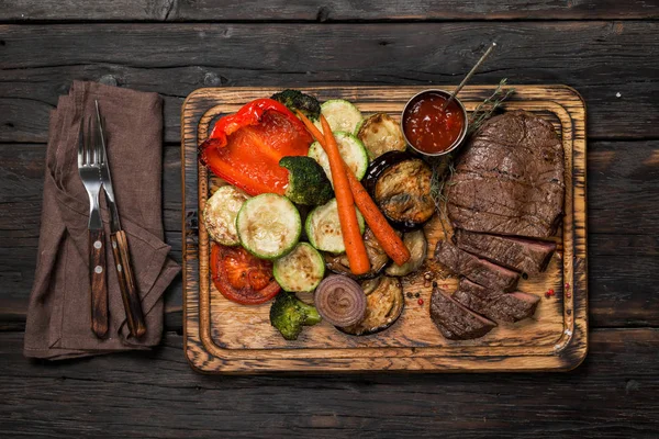 Bife fatiado com legumes grelhados na mesa de madeira — Fotografia de Stock