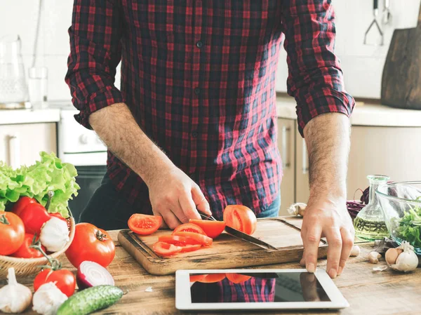 Mann folgt Rezept auf Tablette und kocht gesunde Nahrung — Stockfoto