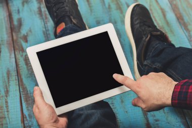 Genç adam ahşap masada oturan beyaz tablet tablet kullanma