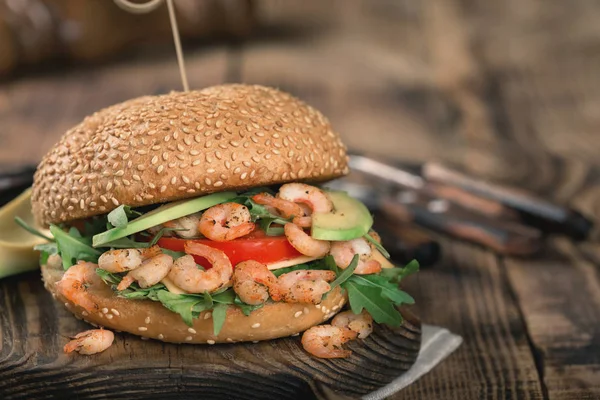 Burger z grillowanymi krewetkami, rukolą i awokado na desce — Zdjęcie stockowe