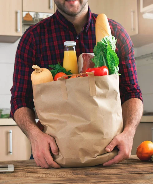 Hombre feliz sosteniendo bolsa de papel llena de diferentes alimentos saludables —  Fotos de Stock