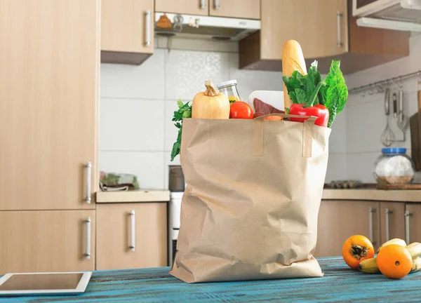 Paper bag full of healthy food on blue wooden table