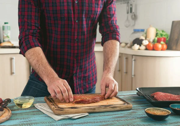 Muž připravuje grilovaný steak na domácí kuchyně — Stock fotografie