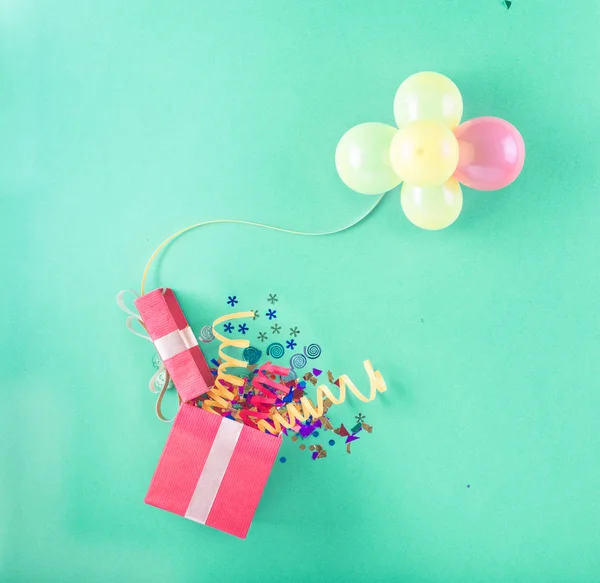 Caja de regalo roja con varios artículos de fiesta y globos — Foto de Stock