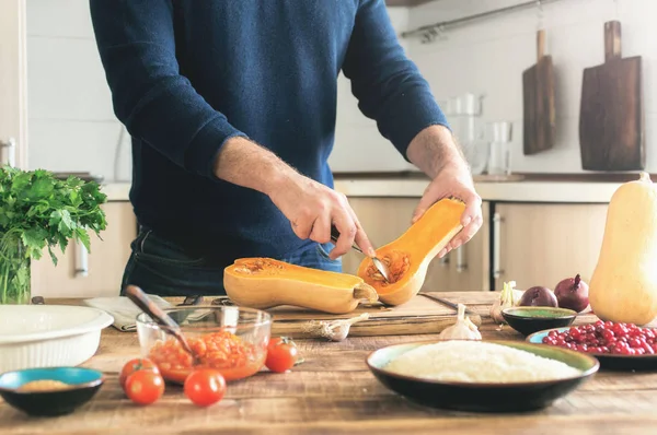 Homem cozinhando uma abóbora em uma mesa de madeira — Fotografia de Stock